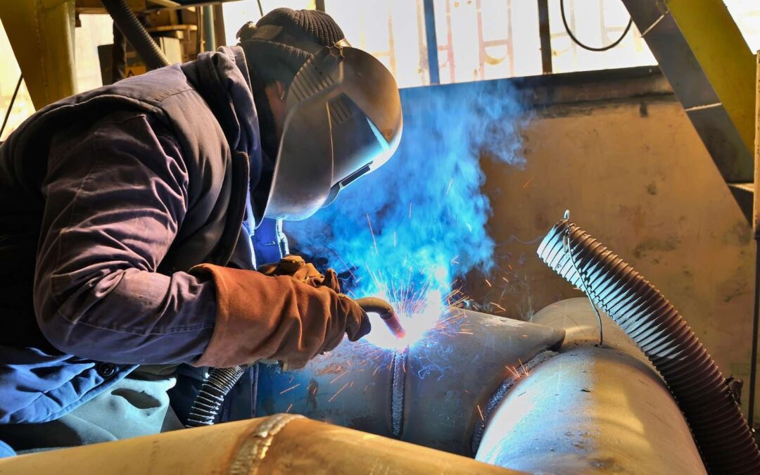 MIG and TIG welding in Michigan welder welding steel pipe together in factory setting